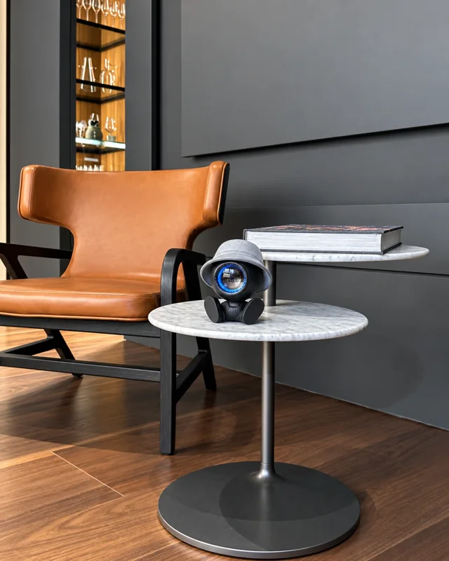 NORAA on a round marble table beside a leather armchair — prototype photograph